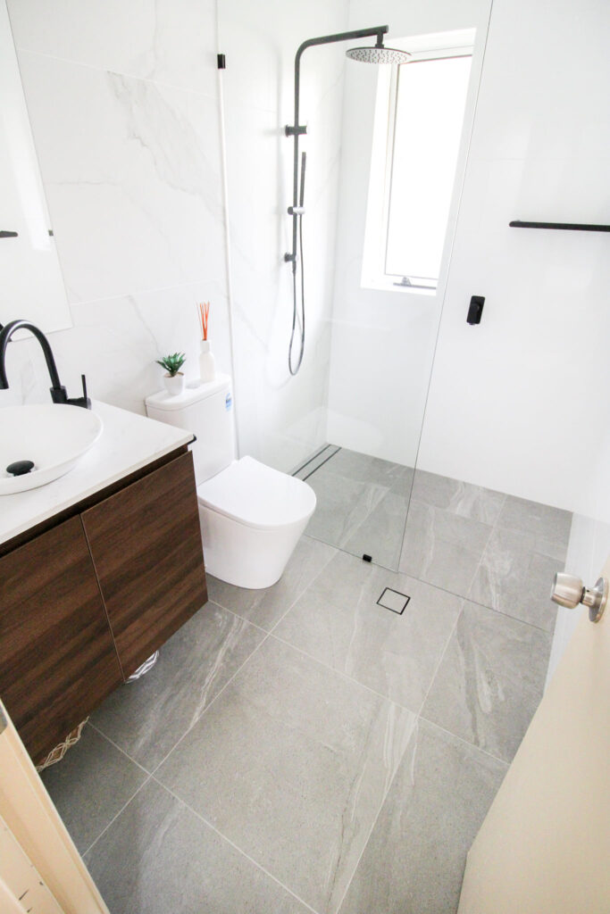 after-bathroom-renovation-black-fixtures-floating-single-vanity-white-toilet-glass-door-shower